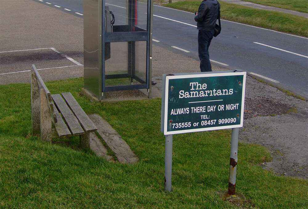 Sign promoting Samaritans near a payphone in the United Kingdom