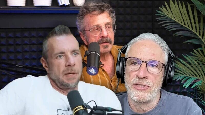 The image shows three middle-aged men engaged in what appears to be a podcast or radio discussion. The man on the left has short, graying hair and is wearing a white shirt; he is speaking into a microphone. The man in the center has curly, graying hair and a mustache, wears glasses, and is dressed in a mustard-colored shirt while speaking into a microphone. The man on the right has white hair and a beard, wears glasses and large headphones, and is also speaking, with a plant visible in the background. The setting includes soundproofing panels on the walls.