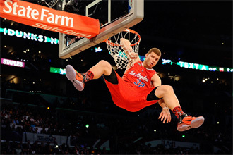 Photograph of Blake Griffin dunking and hanging from the rim wearing a red Los Angeles jersey with the number 32