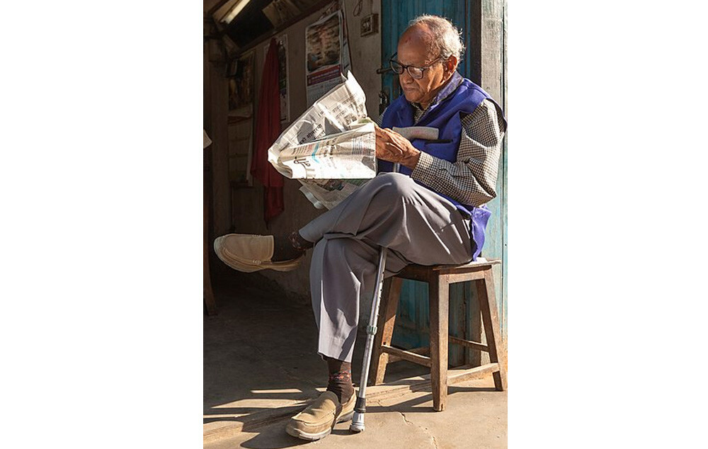 Old man reading newspaper early in the morning at Basantapur