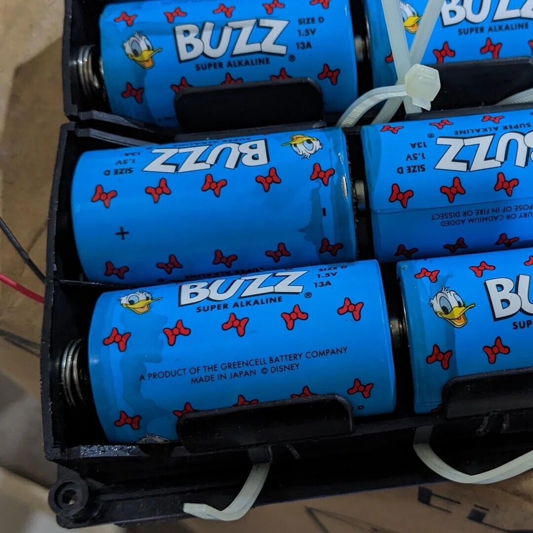 BUZZ SIZE D 1.5V BULL SUPER ALKALINE 13A SUPER ALKALINE VEL AST SIZE D BUZZ AE H zzn SUPER ALKALINE 1.5V SIZE D + POSE OF IN FIRE OR DISSECT URY OR CADMIUM ADDED BUZZ® SIZE D 1.5V 13A SUPER ALKALINE B SUP A PRODUCT OF THE GREENCELL BATTERY COMPANY MADE IN JAPAN © DISNEY