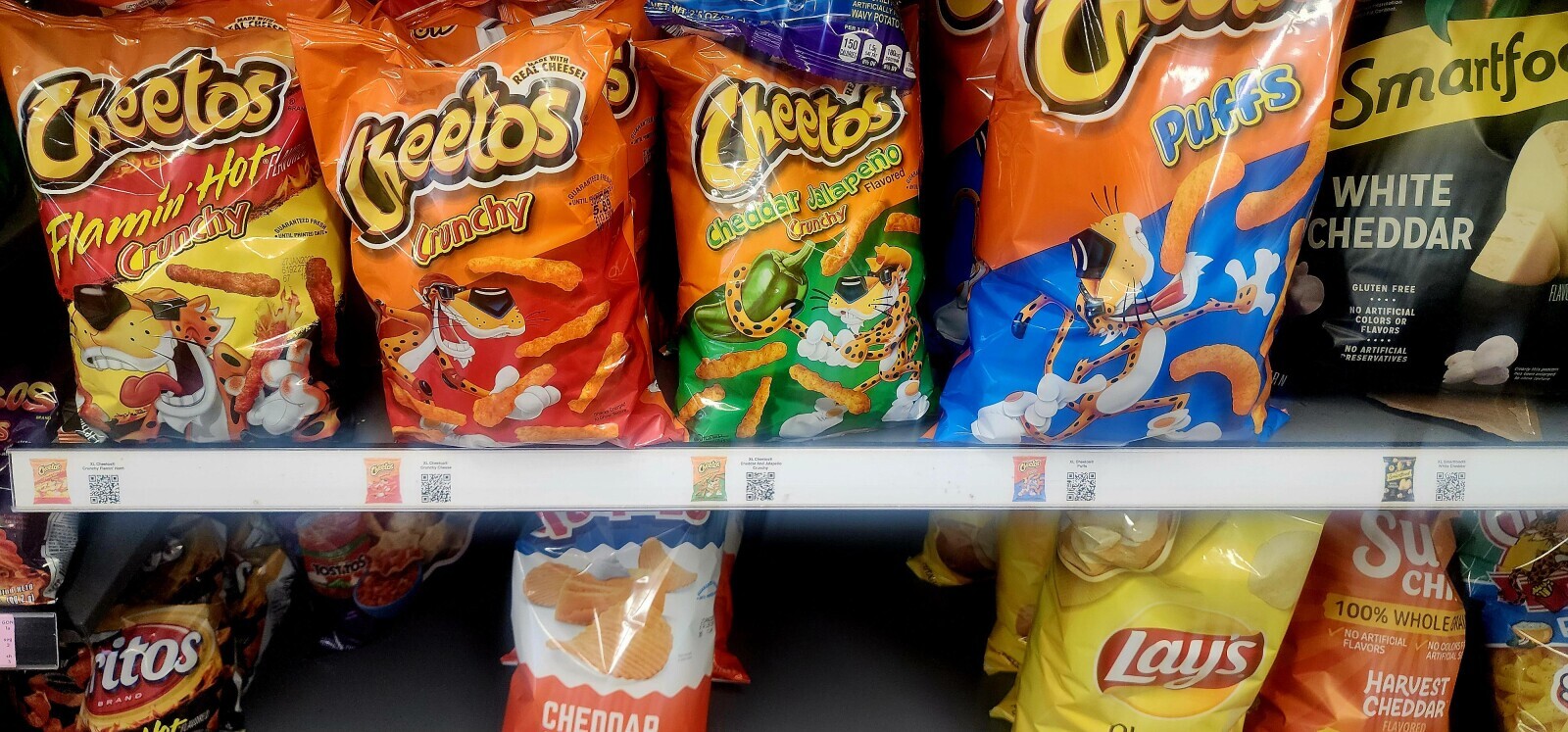 NET WT 25 oz p ARTIFICIALLY intormation WAVY POTATO P.M Content. ALCHEECA MADE WITH PER 1 OZ ou 150 S 1.5g 160mg CALORIES CHEESE! WITH DE SAT FAT DV DE SODIUM DV IT LEIS BRAN ® YOUR Smartfo CReetos GUARANTEER 75 Cheetos Puffs Cheetos REAL MADE DONE GUAR Flavored LUNTE GUARANTEED FRESH •UNTIL WHITE B GUARANTEED FRESH 21132404 Flamin Hotze the UNTIL PRINTED DATE Crunchy CHEDDAR Cronchy Cheddar Jalapeño Crunchy 27JAN2000 619227 67 GLUTEN FREE FLAV NO ARTIFICIAL COLORS OR FLAVORS NO ARTIFICIAL PRESERVATIVES Dienro mis papeam RN mas entarged OS BRAND Snacks Enterped DE Show Texture S XL Smarttoods XL Cheetos Chedder Cheetose XL Cheetosh Puth Crunchy Flamor Hom Crunchy Cheetos
